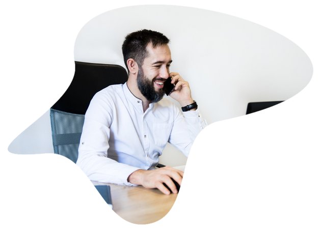 Mann sitzt am Schreibtisch vor Laptop und telefoniert